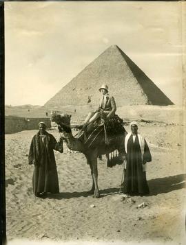 Woman on camel at Cheops Pyramids, two men standing