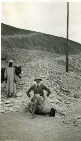 Woman sat on rock in Egypt. Man with donkey behind