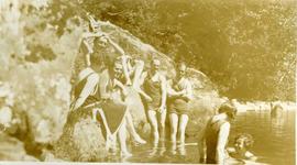 Large group on a riverbank, some swimming