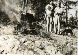 Muriel with unknown man, burning a stump