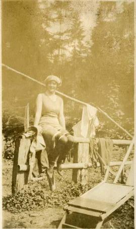 woman in stockings and bathing costume seated on a fence