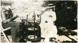 two women knitting outdoors by a tea trolley