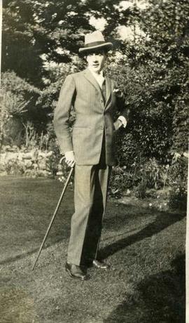 Clifton Webb in suit with cane on a lawn