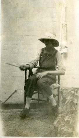 seated woman waving knitting needles