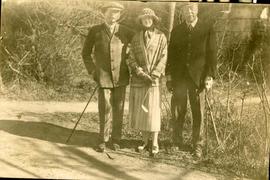 Two men and a woman with golf clubs, in winter