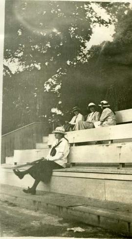 Schoolgirls sat on bleechers by a tennis court