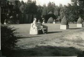 Muriel Dunsmuir on a carved bench, Hatley Park