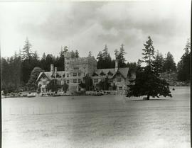 Hatley castle from south east at a distance, showing fence on lawns and a bench under the cedar tree.