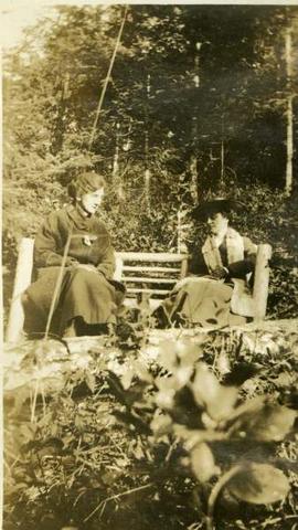 two women on a bench in a wooded area