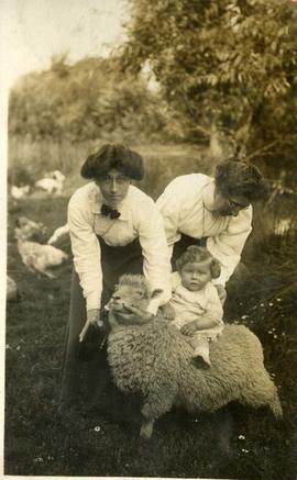 two women with a toddler and a sheep