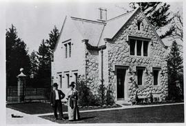 Sooke Road Gatehouse with a man and woman (and cat) in front