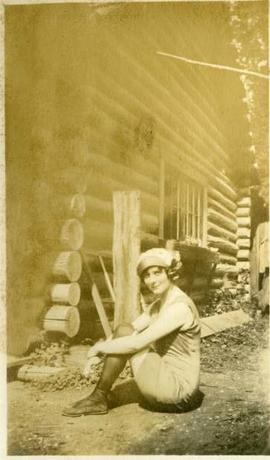 woman seated in bathing costume and stockings outside cabin